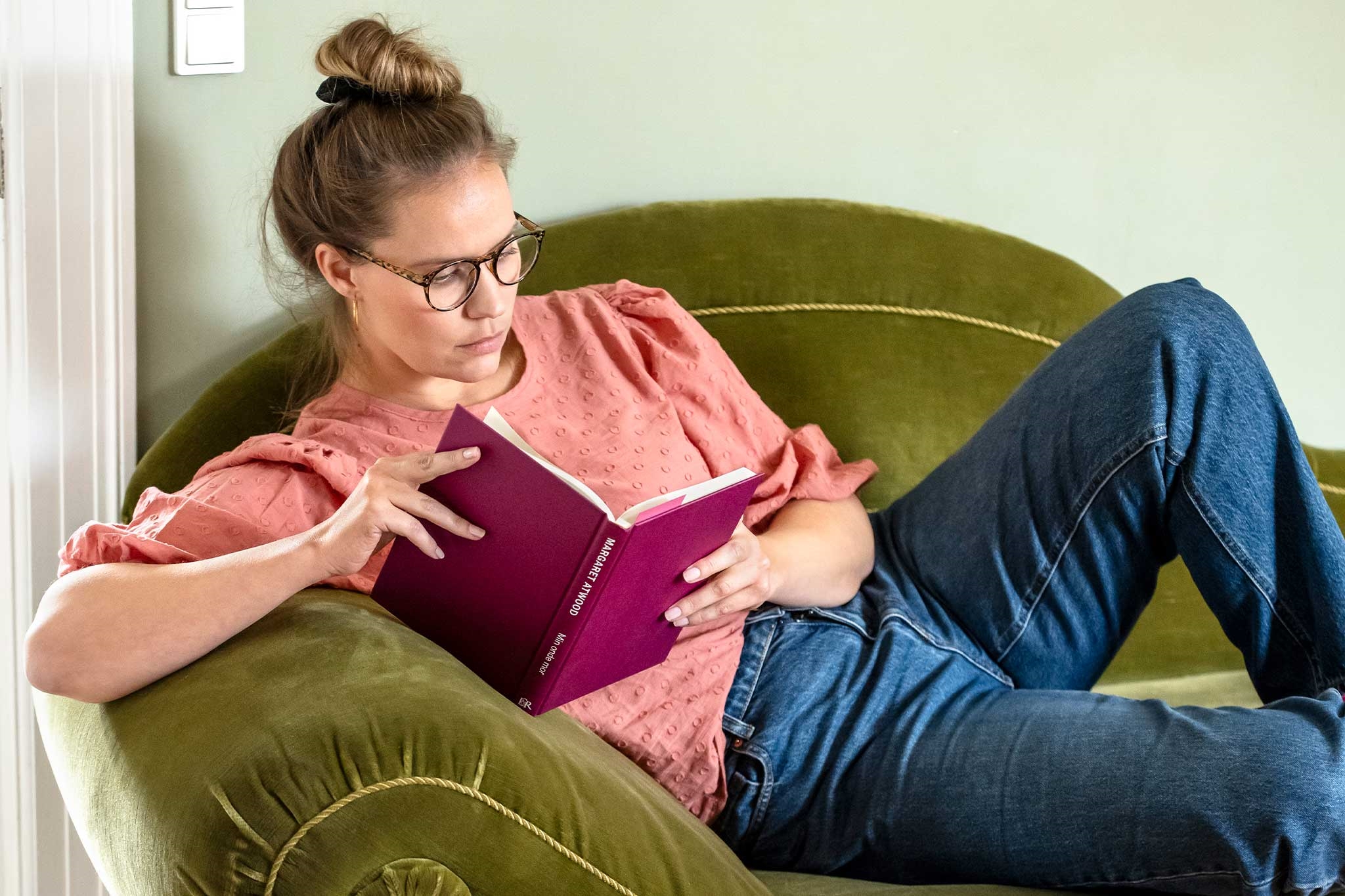 Kvinde læser bog på sofa